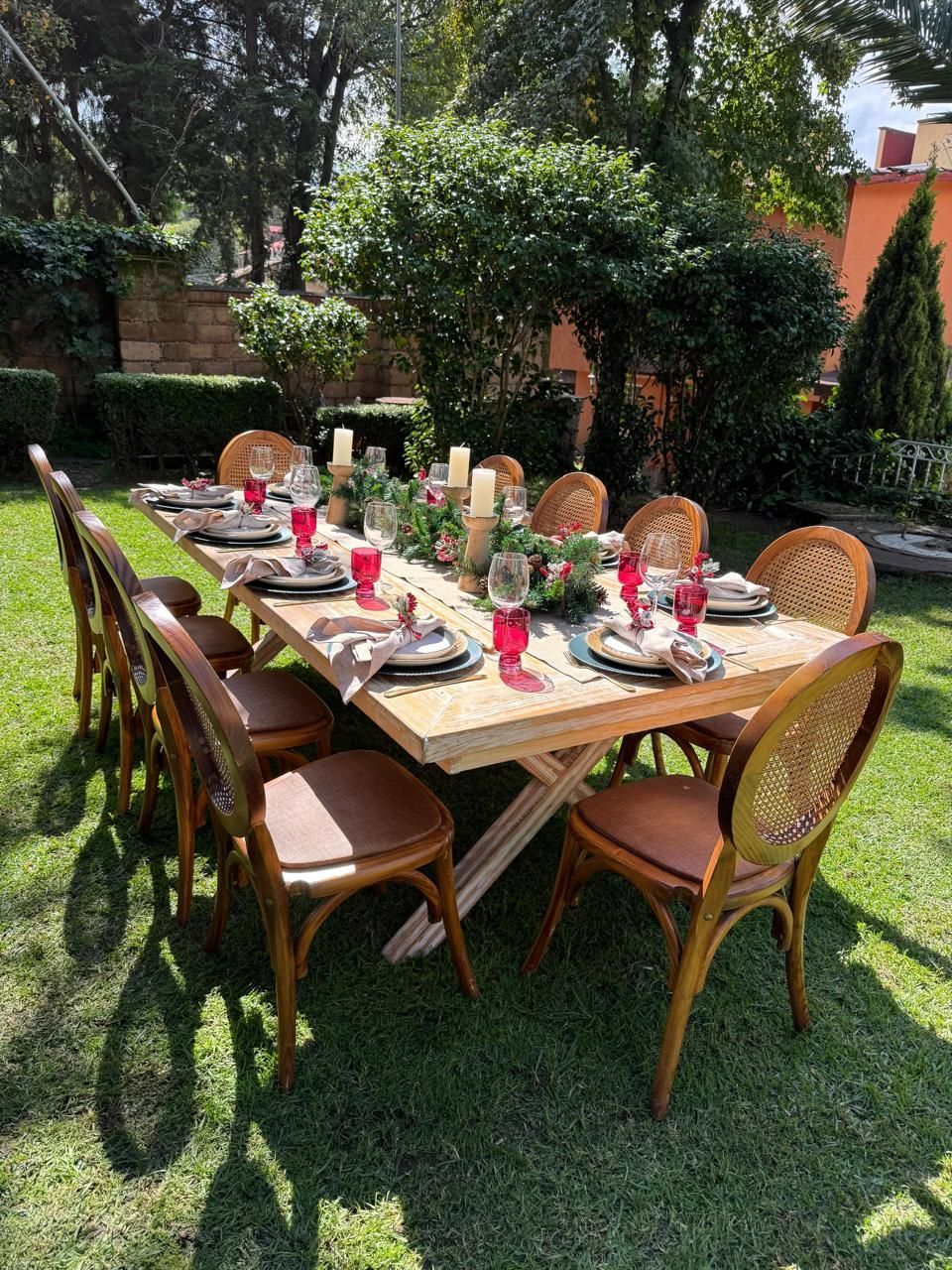 Juego de mesa de comedor al aire libre con cubiertos y decoraciones sobre césped verde.