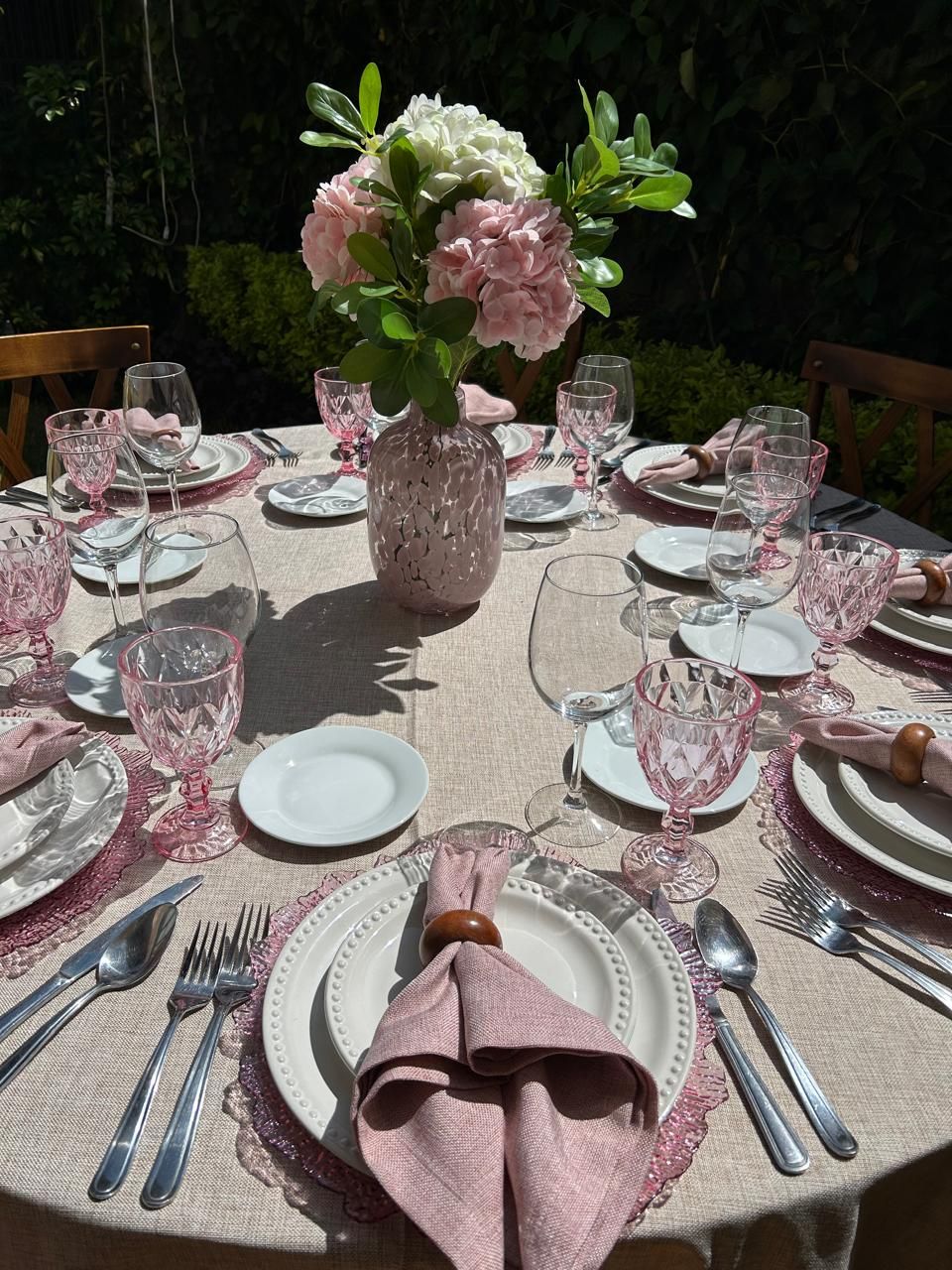 Juego de mesa de comedor para exterior con detalles rosas y centro de mesa floral.
