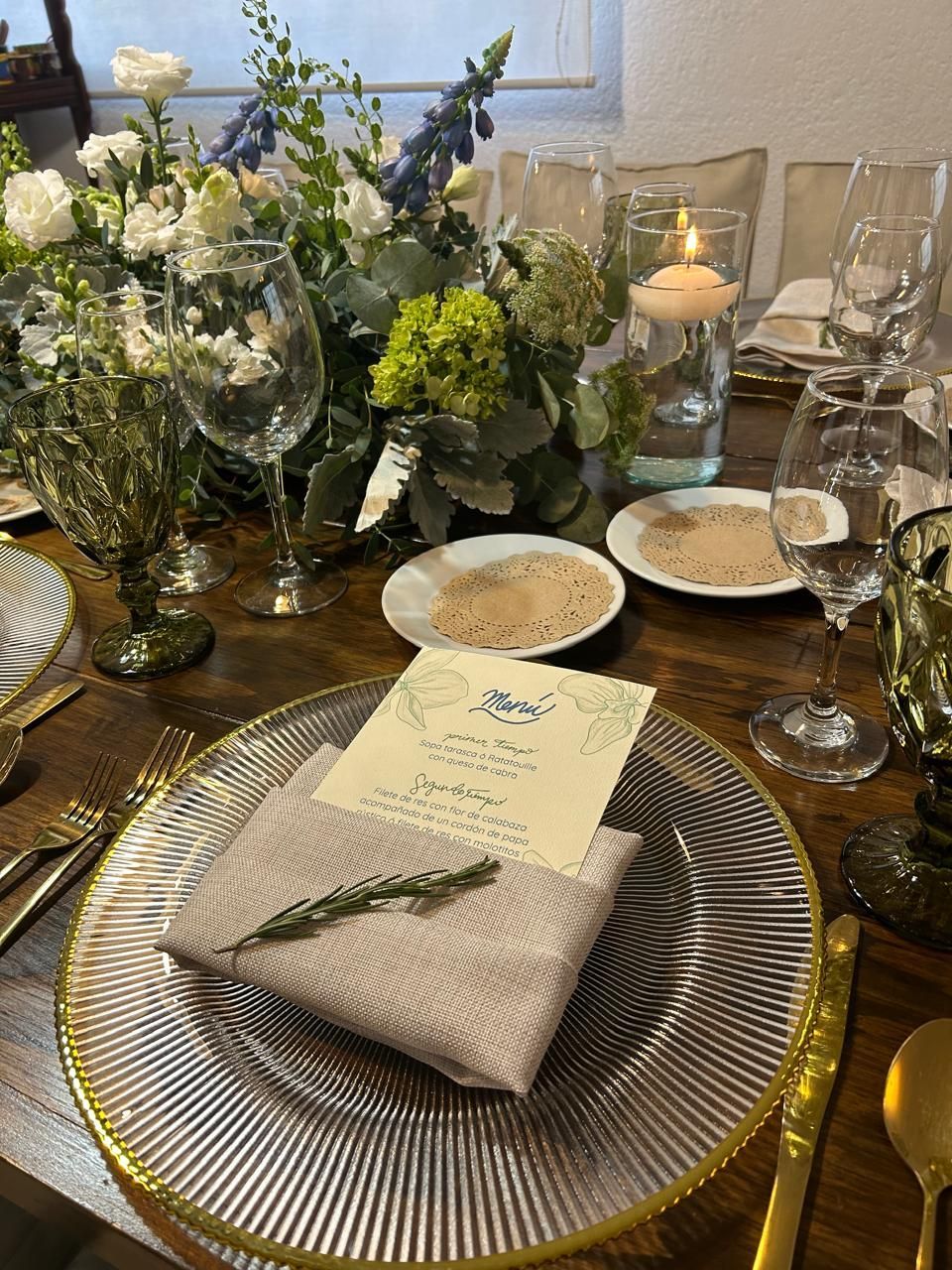 Elegante juego de mesa de comedor con centro de mesa floral, velas y cubiertos.
