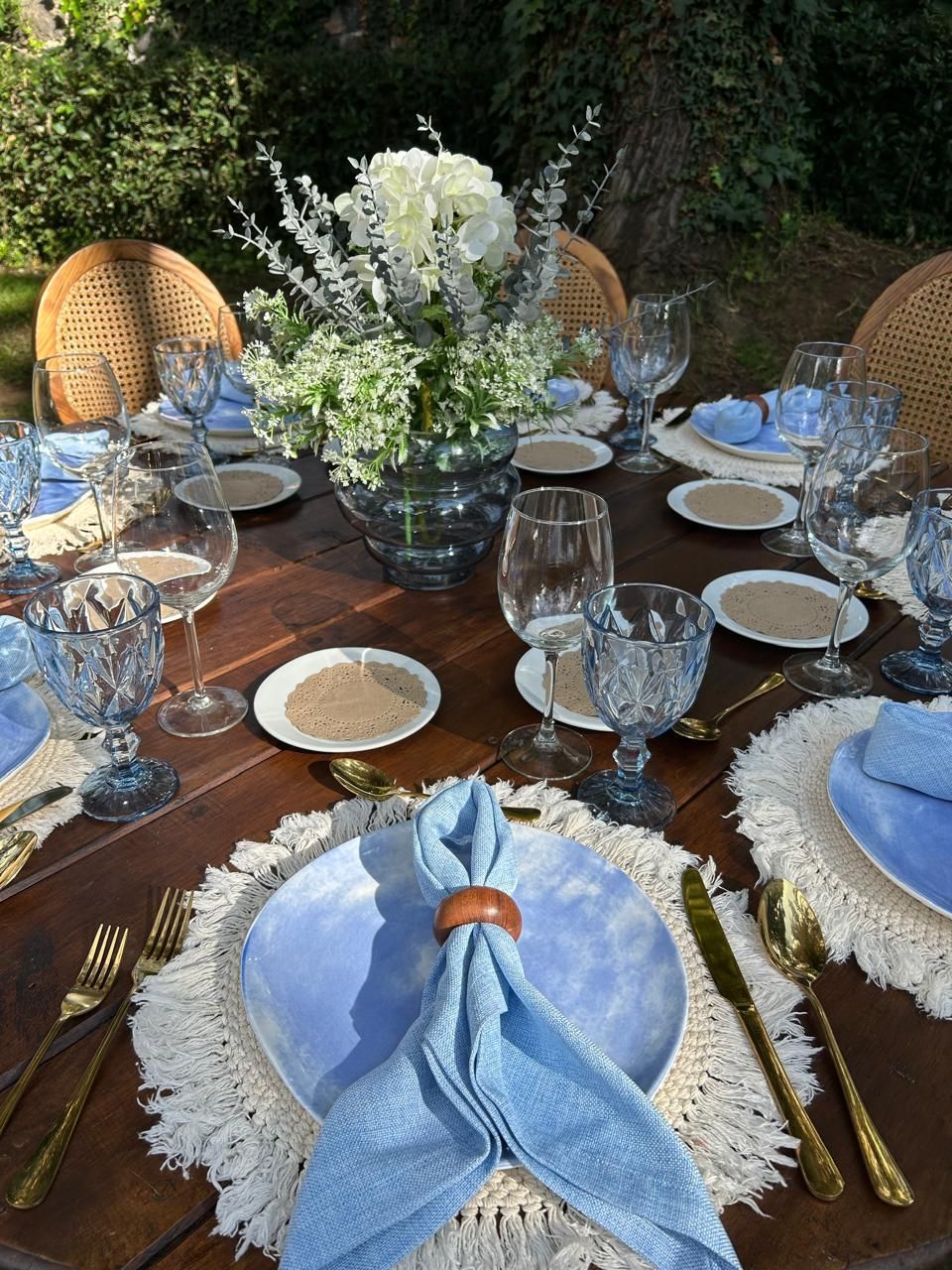 Juego de mesa de comedor para exterior con detalles azules y centro de mesa floral.