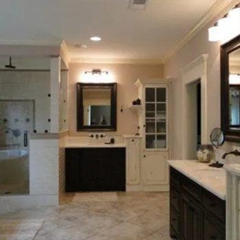 Bathroom with dark vanity, mirror, white cabinet, glass shower, and beige walls.