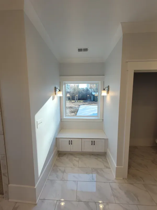 Hallway with a built-in window seat. White cabinets, gray walls, window with trees.