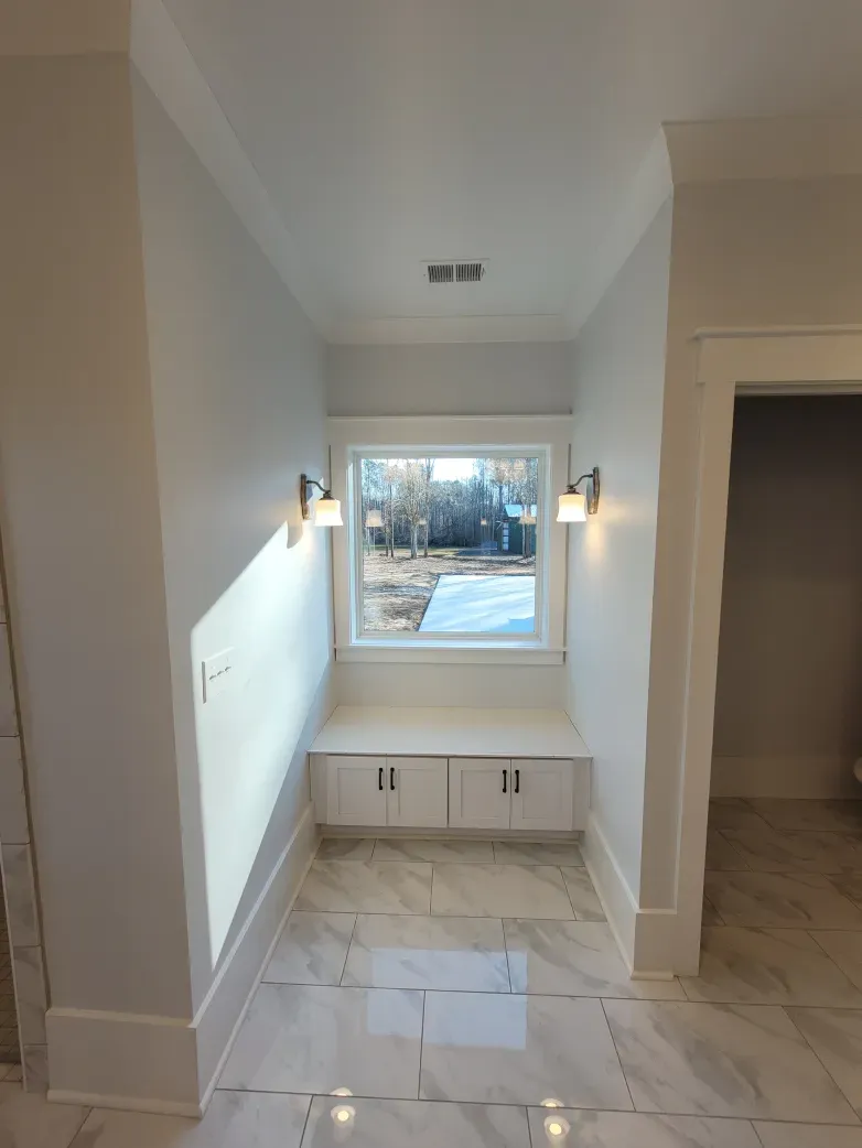 Hallway with marble floor, window seat, two sconces, and white trim.