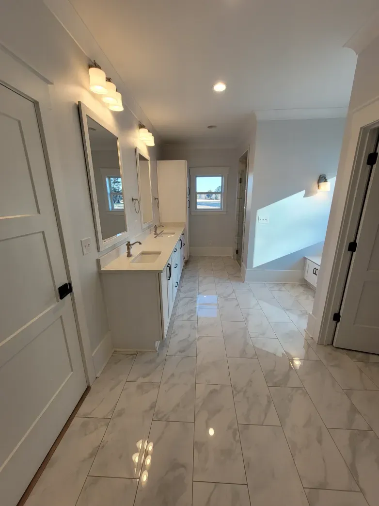 Bright white bathroom with marble floors, double vanity, and natural light.