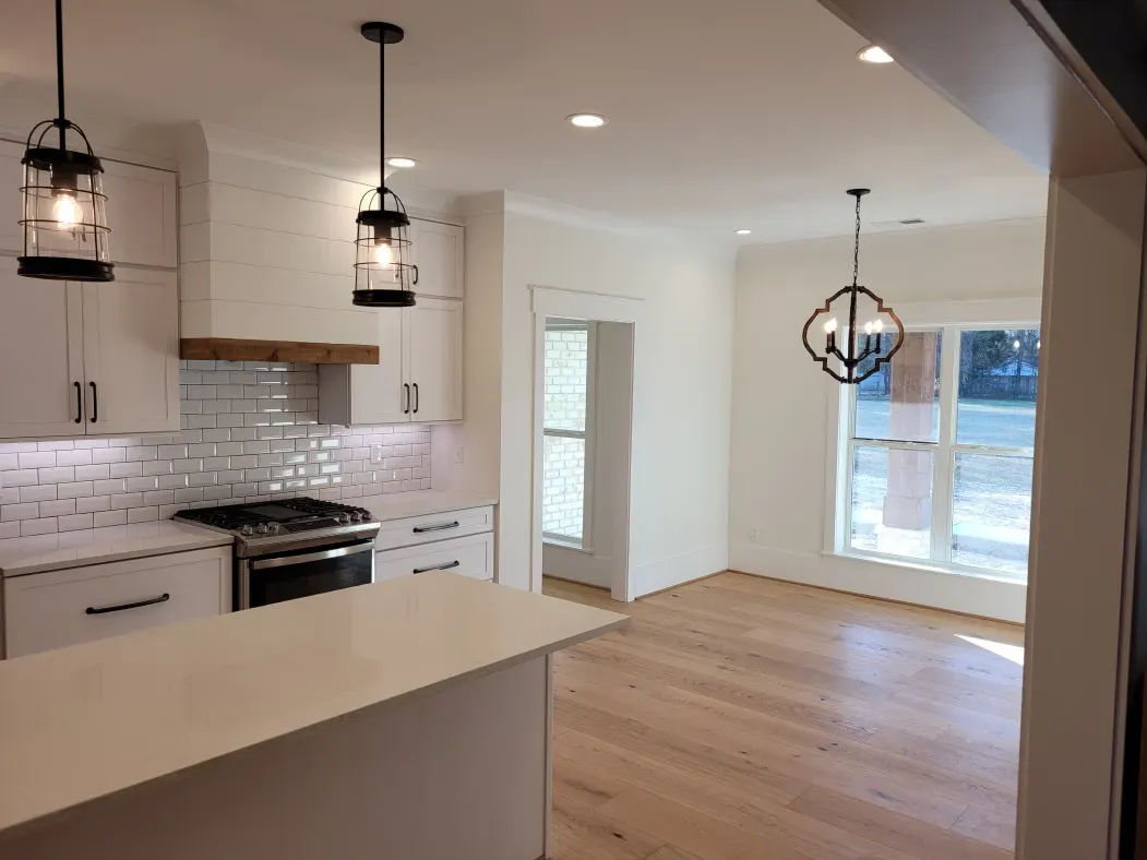 Kitchen with white cabinets, wood floors, and light fixtures.