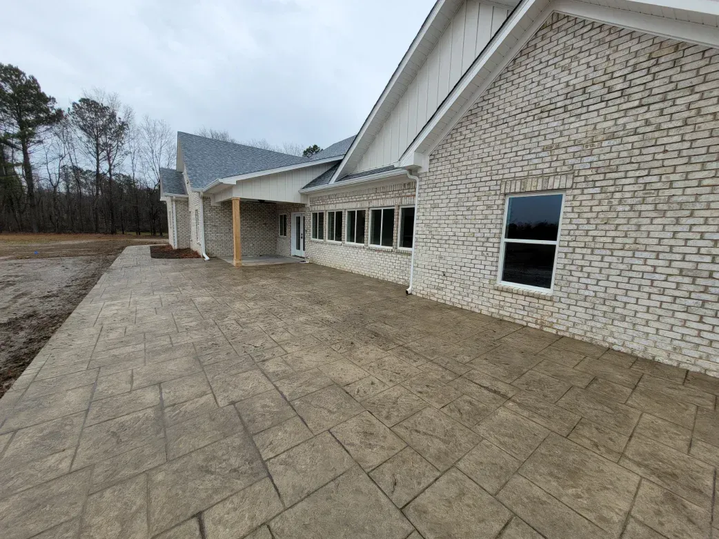 Exterior view of a brick building with a stamped concrete patio on a cloudy day.