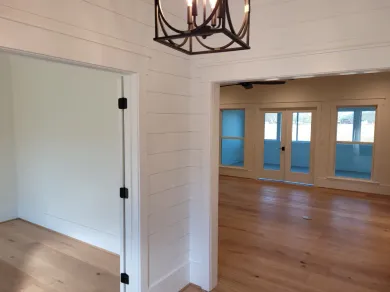 Interior view: doorway leading to room with french doors and hardwood floors, light walls.
