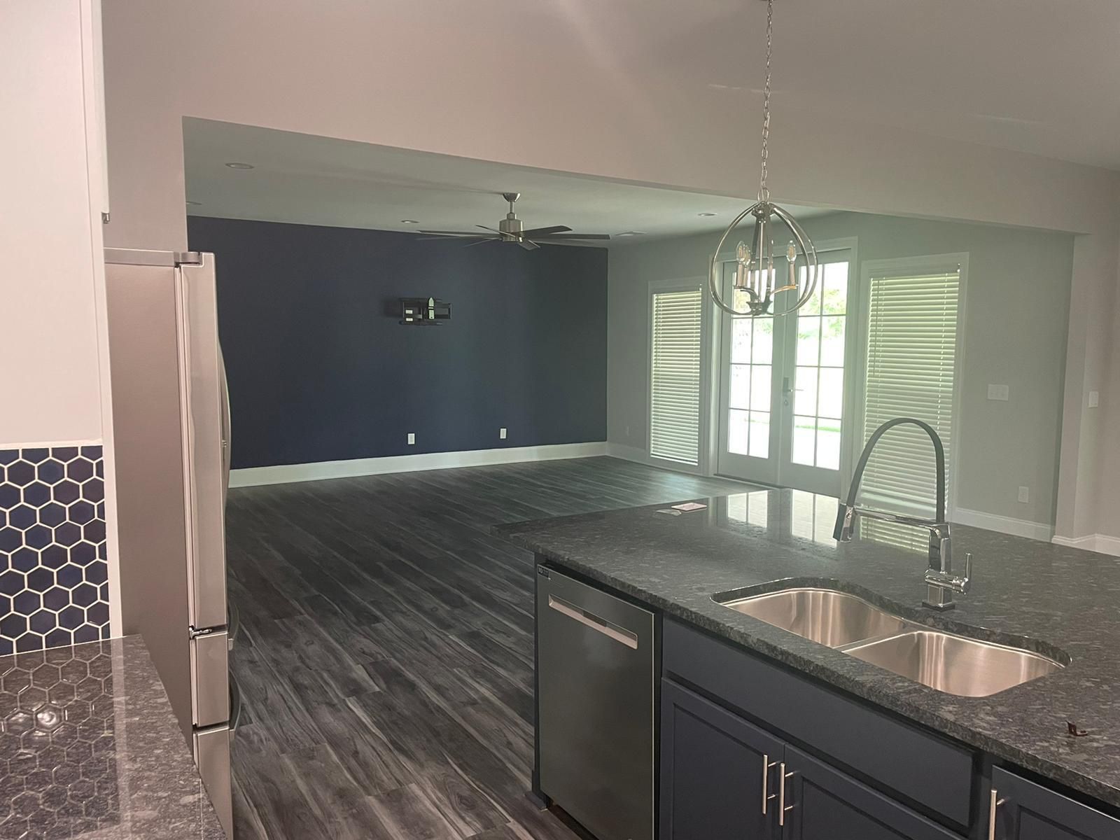 Kitchen with island, and stainless steel appliances, opening to a living room.