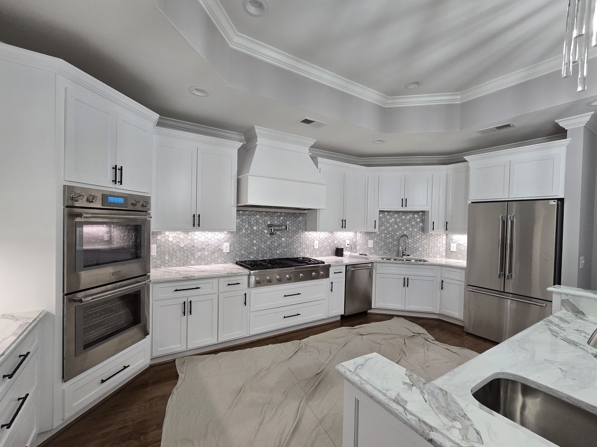 White kitchen with stainless steel appliances and marble countertops.