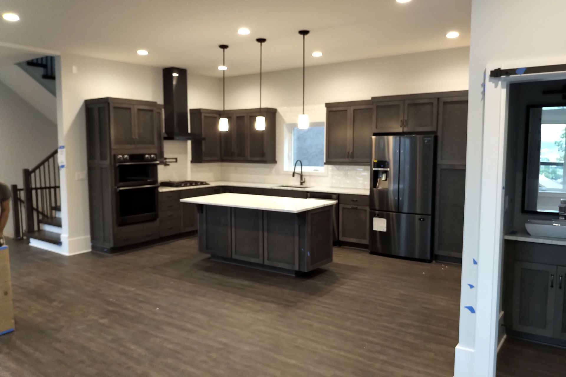 Modern kitchen with dark gray cabinets, stainless steel appliances, and a white island.