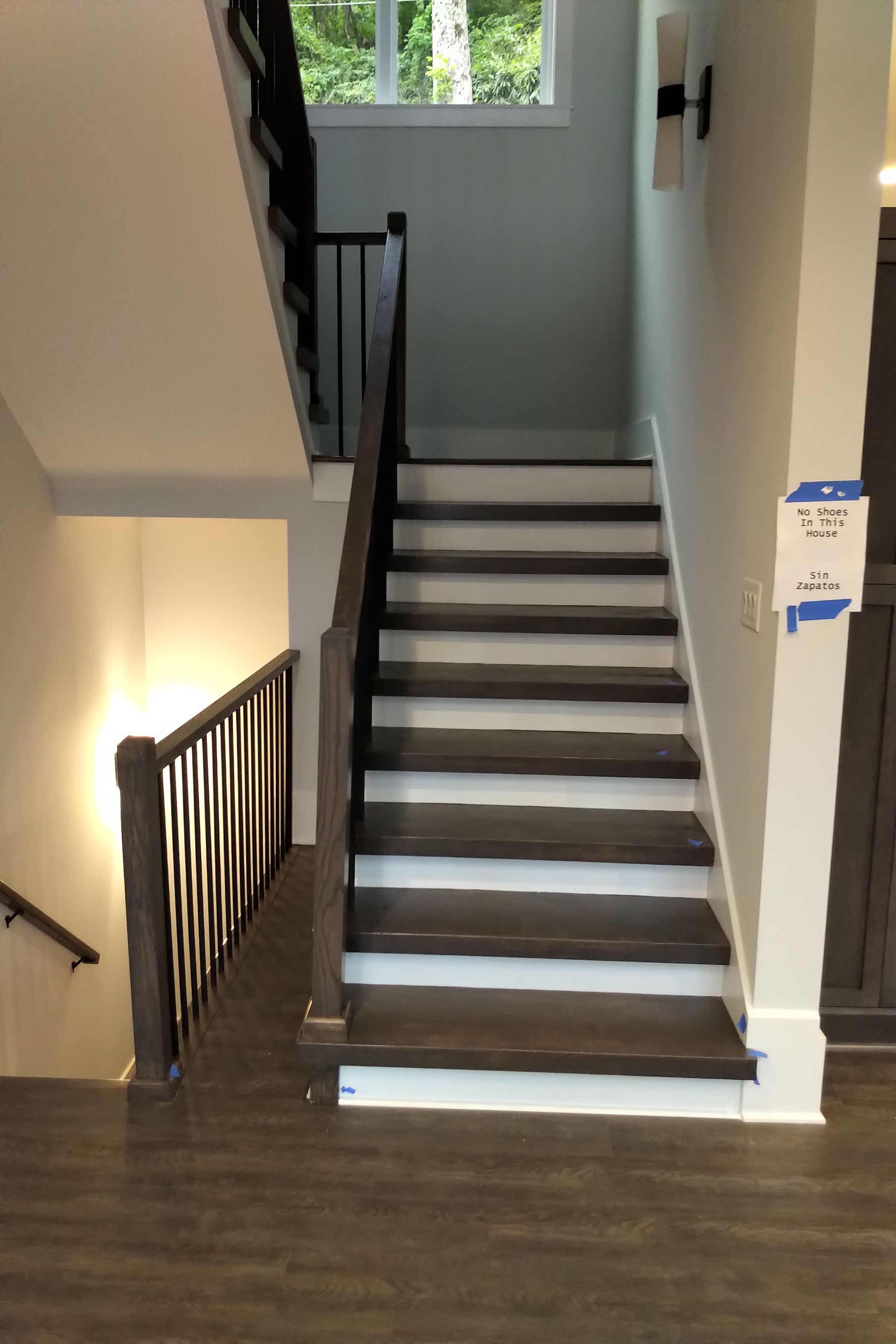 Dark wooden staircase with white risers, leading upwards. Handrails on either side.