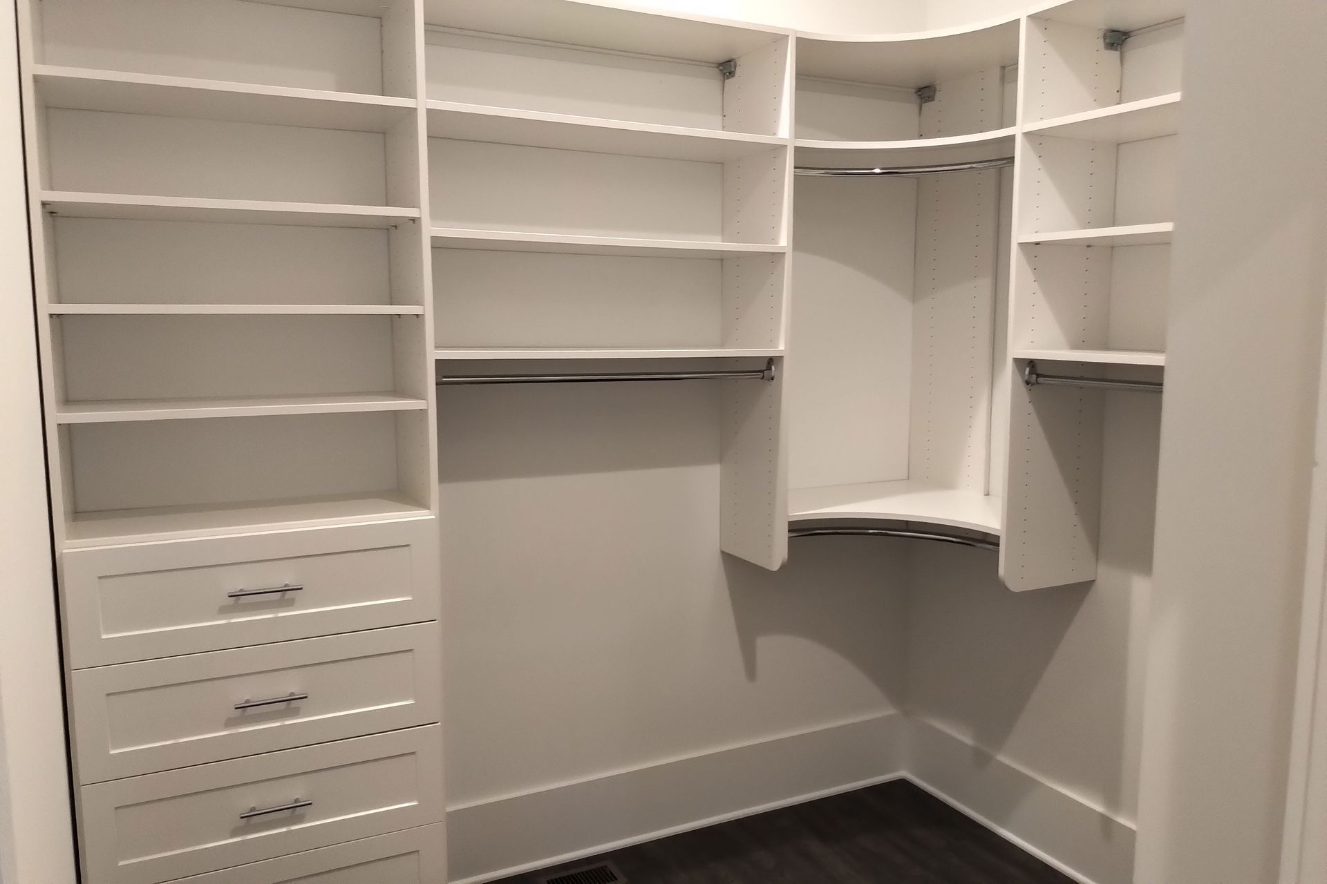 White custom closet with shelves, drawers, and hanging rods.