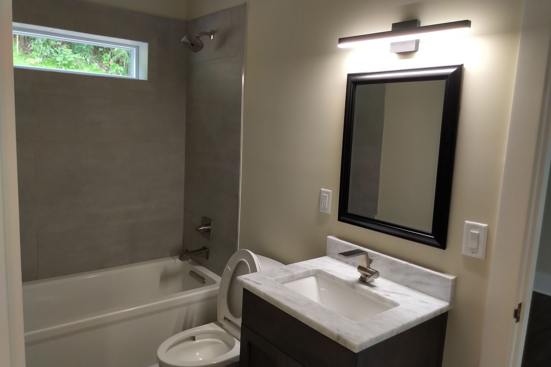 Bathroom with a bathtub, toilet, vanity with mirror, and overhead lighting.