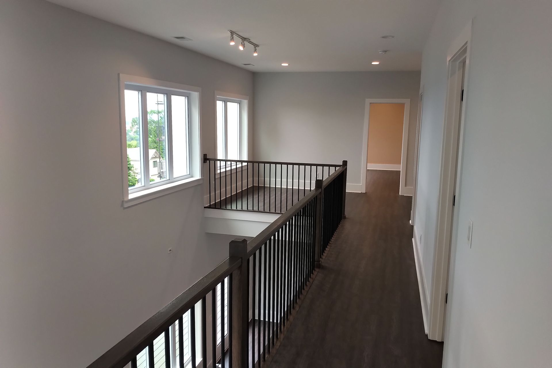 Interior view of a second-floor hallway with a dark wood floor and a railing overlooking a lower level.