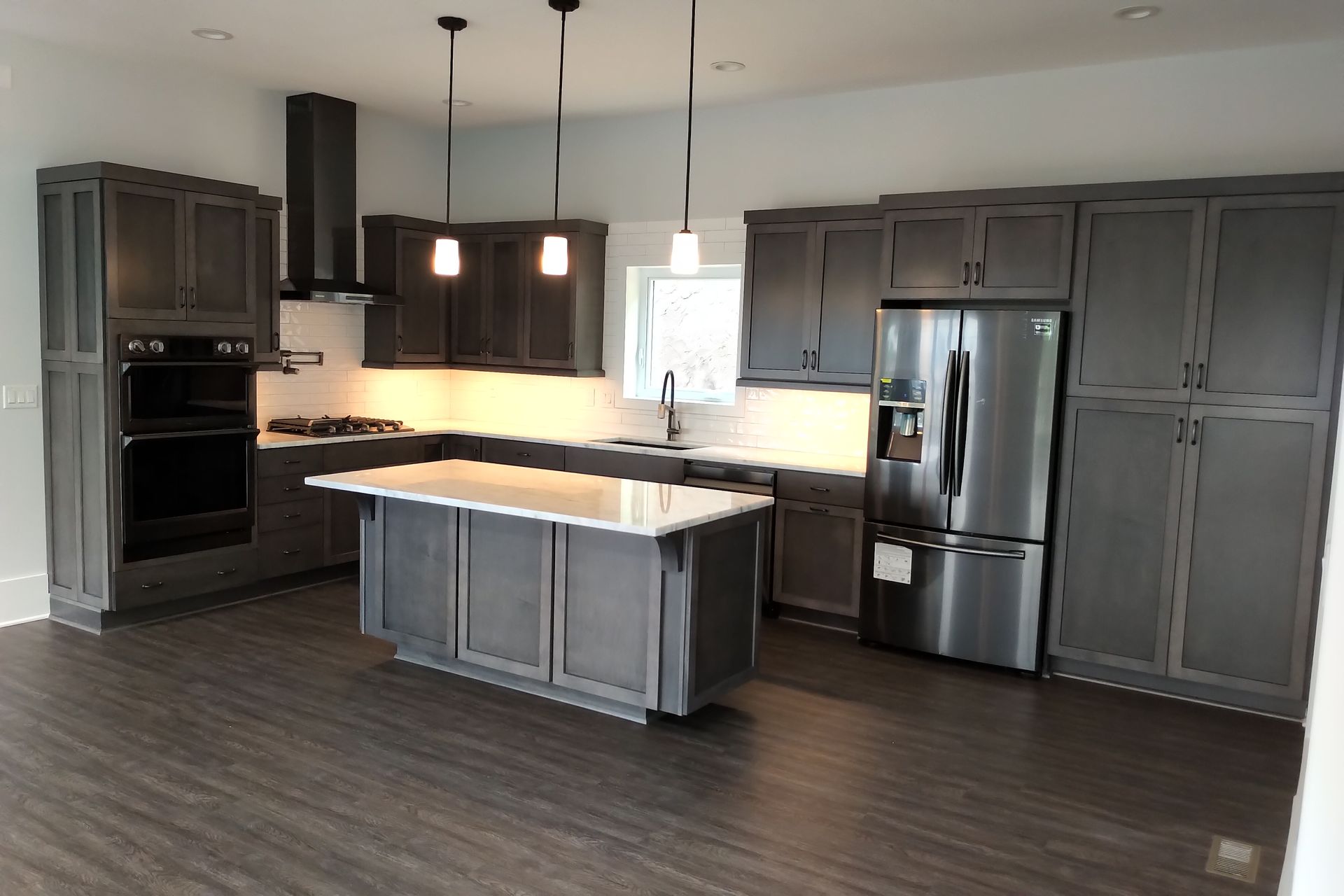 Modern kitchen with gray cabinets, stainless steel appliances, and a white countertop island.