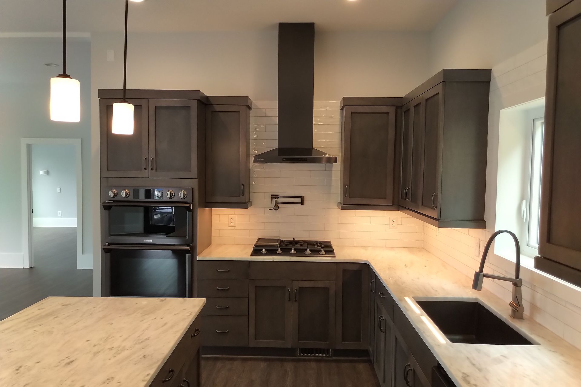 Dark gray kitchen with granite countertops, stove, and cabinets.
