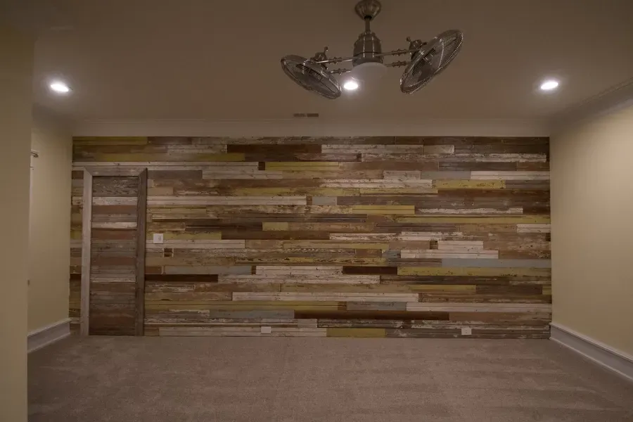 Room with a multi-toned wooden accent wall, recessed lighting, ceiling fan, and carpet flooring.