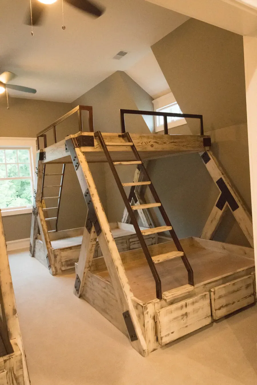 Rustic-style bunk beds with ladders in a bedroom. Beige walls and carpet.