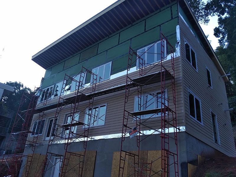 Building exterior under construction; brown siding, scaffolding, windows.