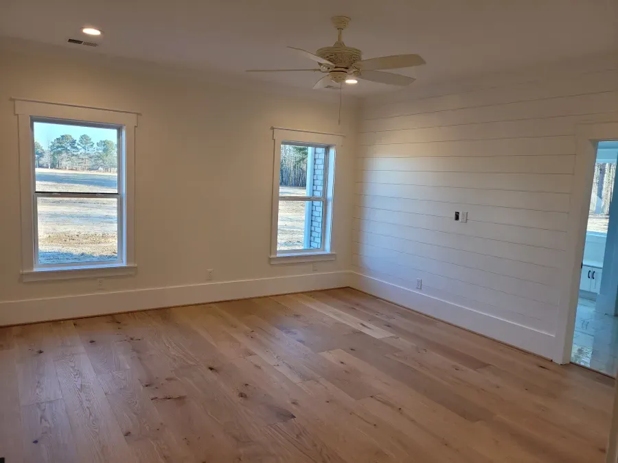 Bright bedroom with wood floor, two windows, and a shiplap accent wall.