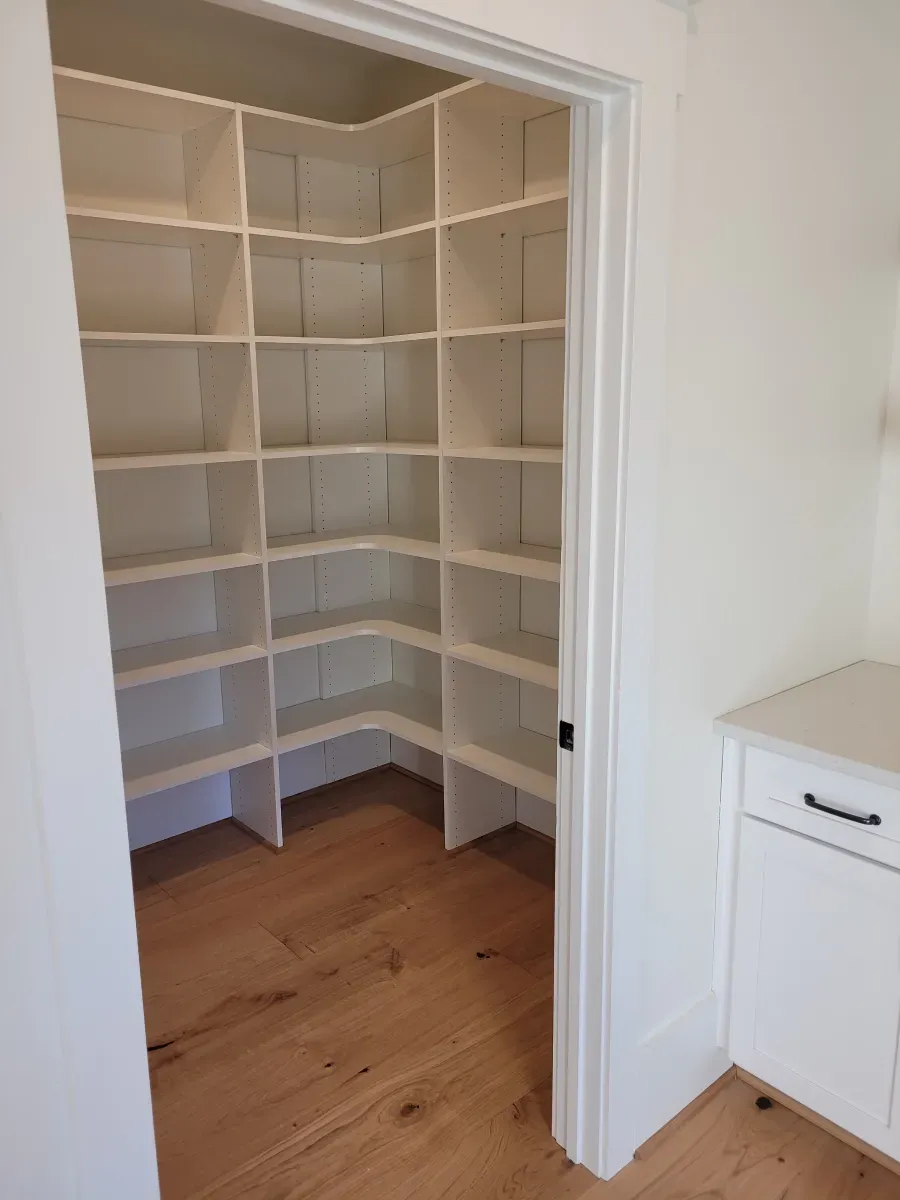 Corner pantry with white shelves and light wood floor.