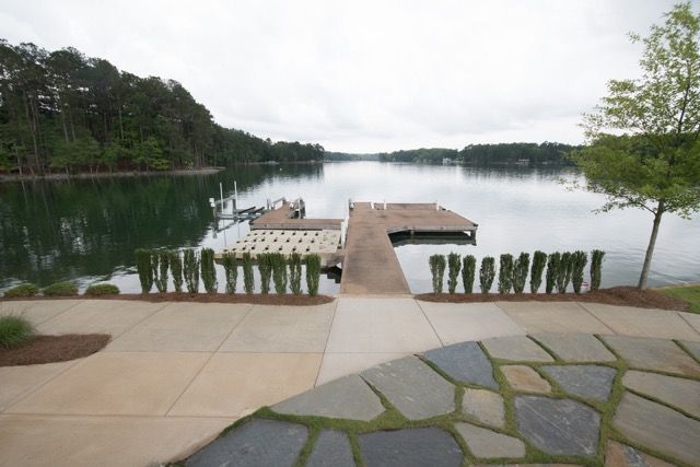 Dock extending over calm water, trees in the background, cloudy sky.