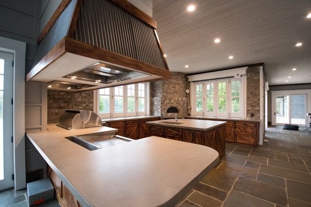 Rustic kitchen with stone walls, wooden cabinets, and a large range hood.