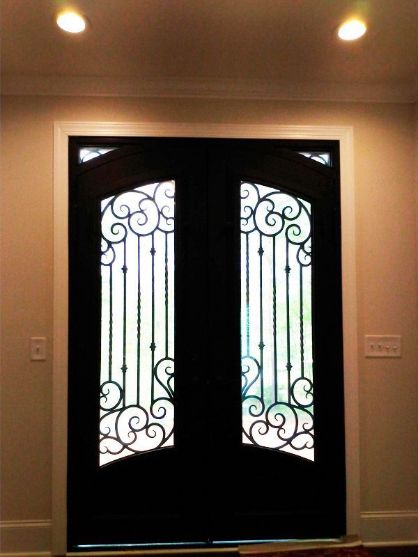 Dark front door with arched windows and ornate ironwork.