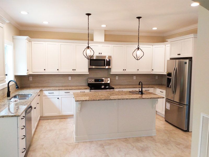 White kitchen with granite countertops, stainless steel appliances, and an island.
