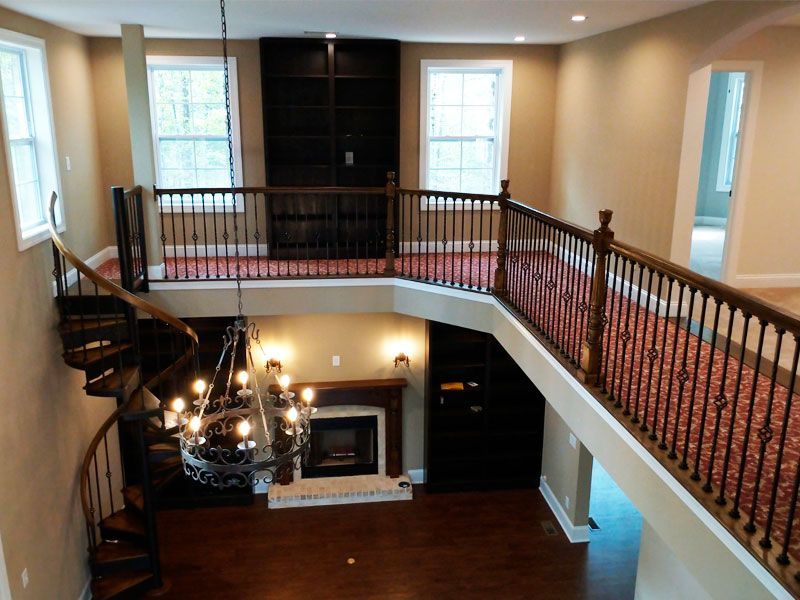 Spacious two-story room with a spiral staircase, balcony, fireplace, and chandelier.