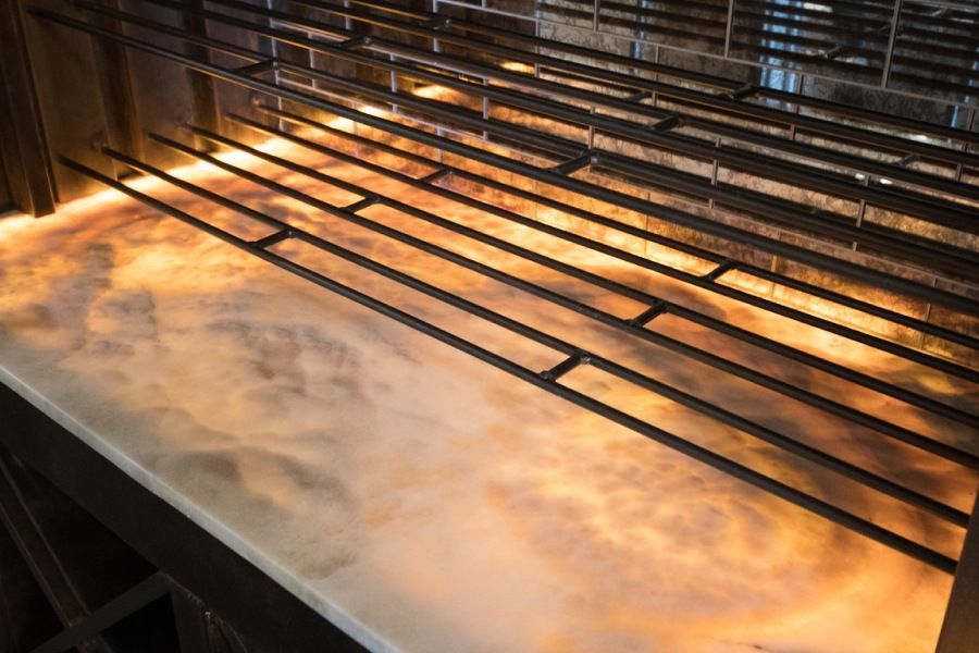 Steel grill over a fiery, hazy industrial setting.