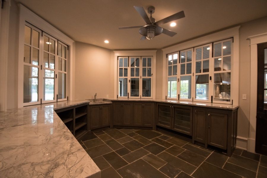 Interior of a bar area with stone flooring, built-in cabinets, large windows, and marble countertops.