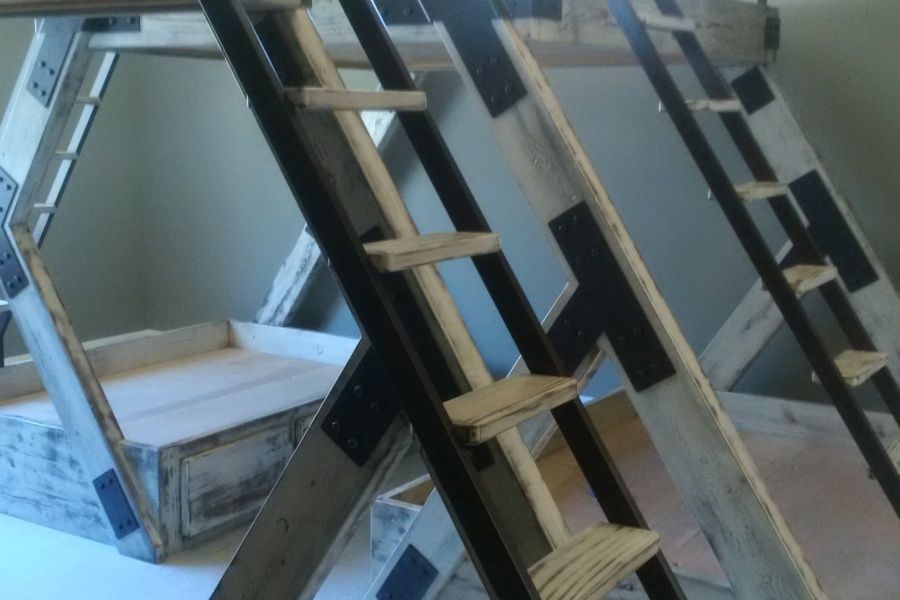Wooden geometric play structure with ladders and storage space, painted white and accented with black.