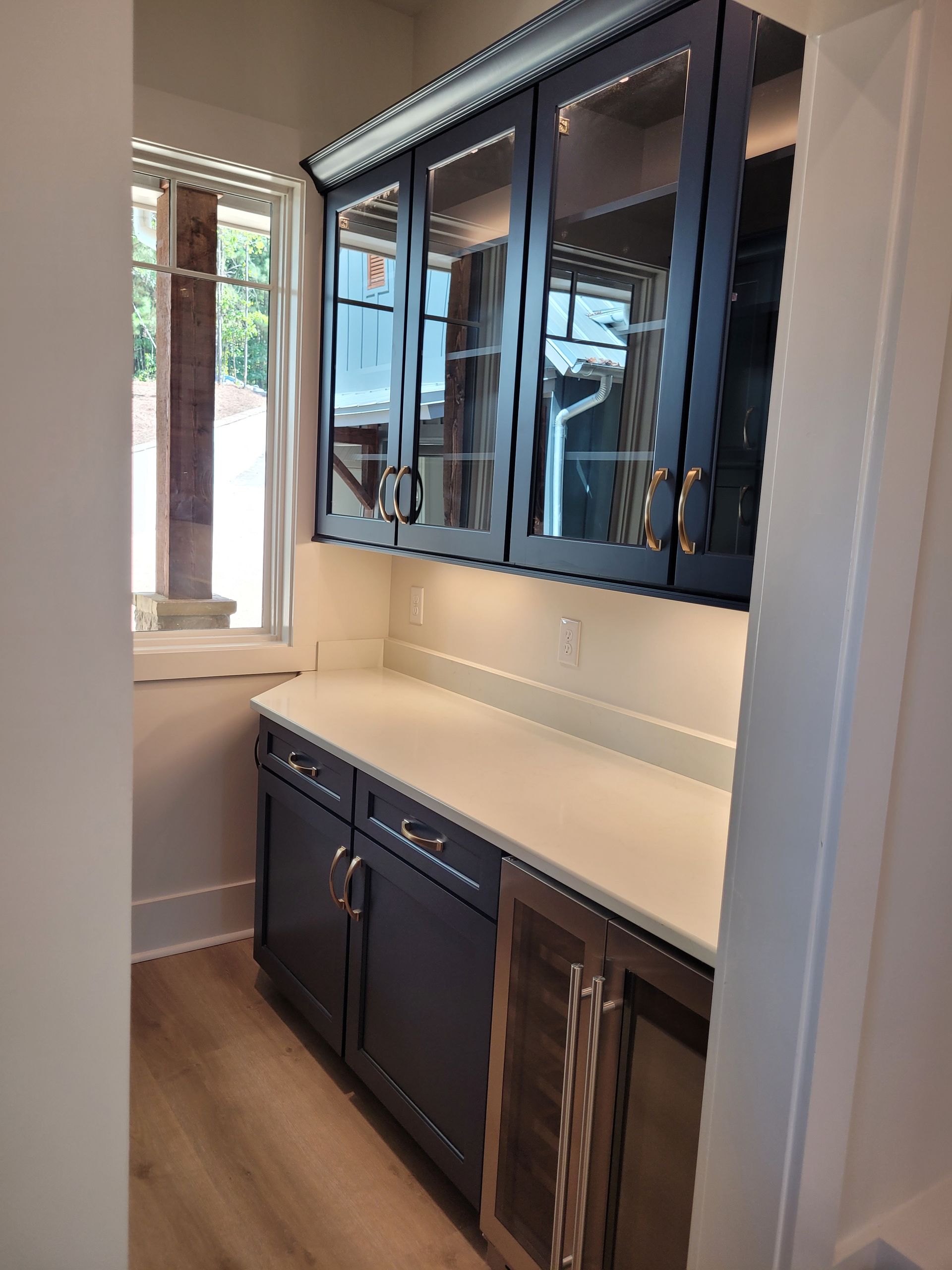 Dark blue built-in pantry with glass-fronted cabinets, white countertop, and a wine cooler.