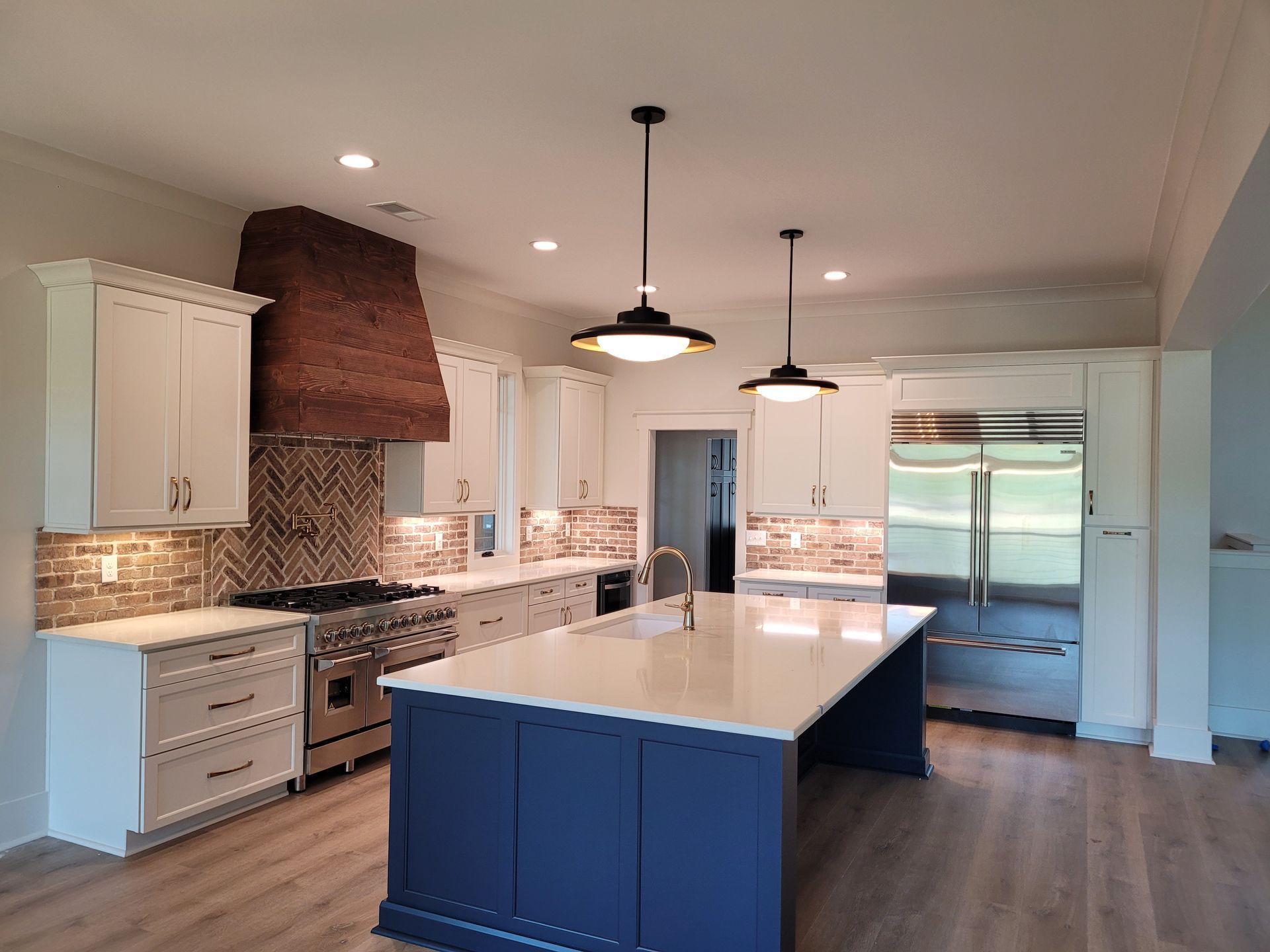 Modern kitchen with blue island, white cabinets, copper hood, and stainless steel appliances.