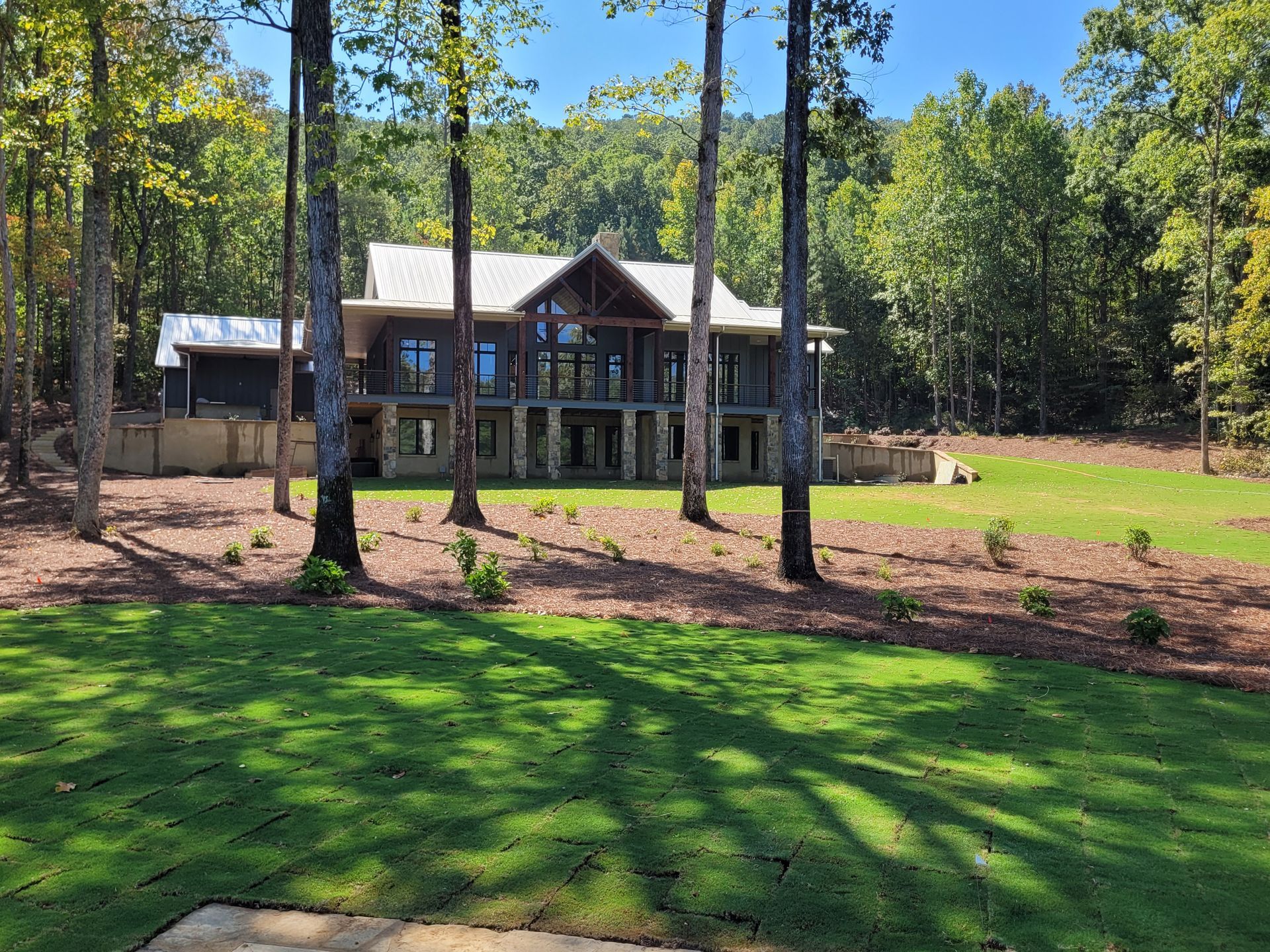 Large modern house with many windows surrounded by trees and green lawn.