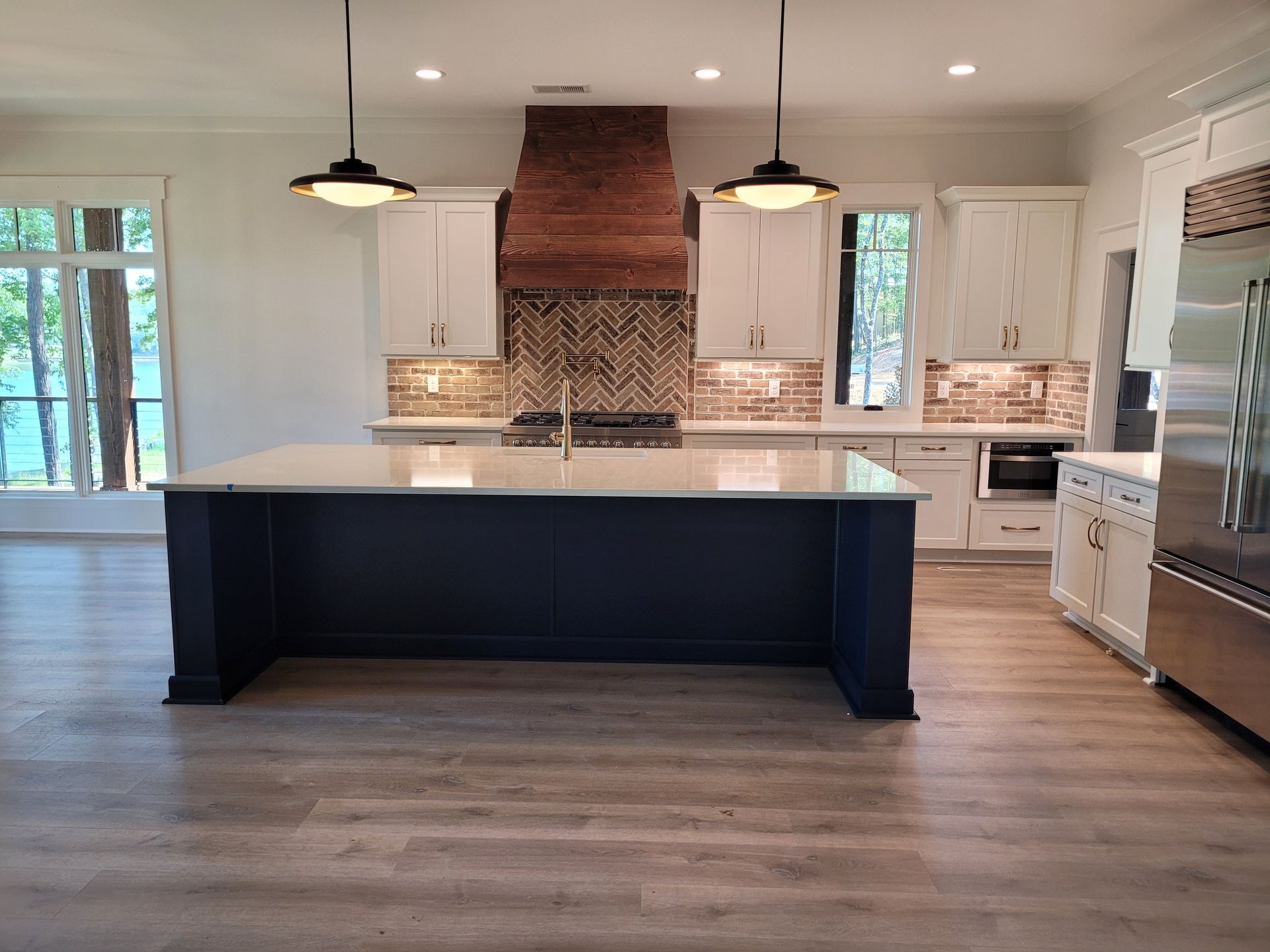 Modern kitchen with navy island, white cabinets, and wooden range hood.