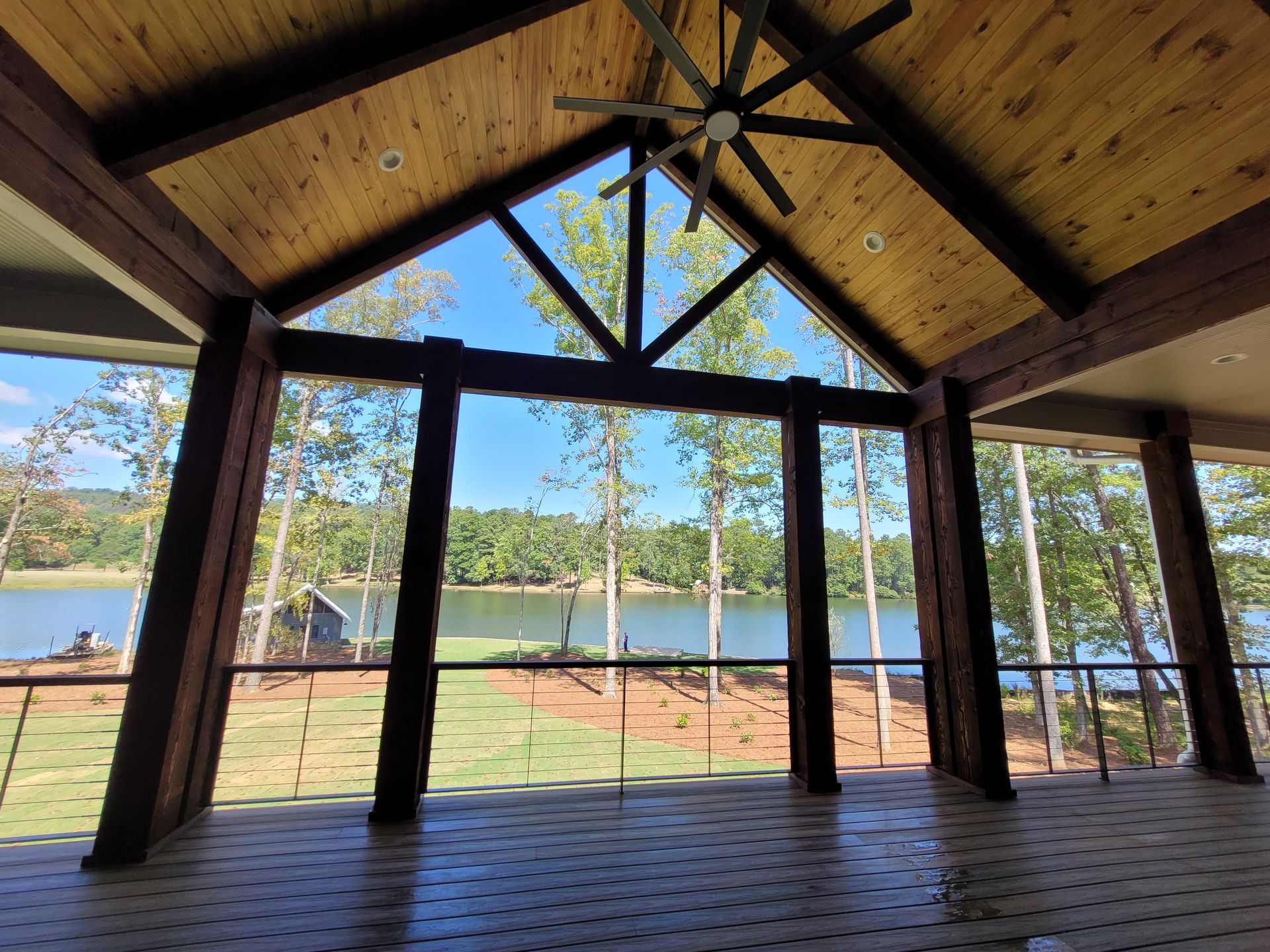 Covered porch with a lake view, wood beams, and a ceiling fan.