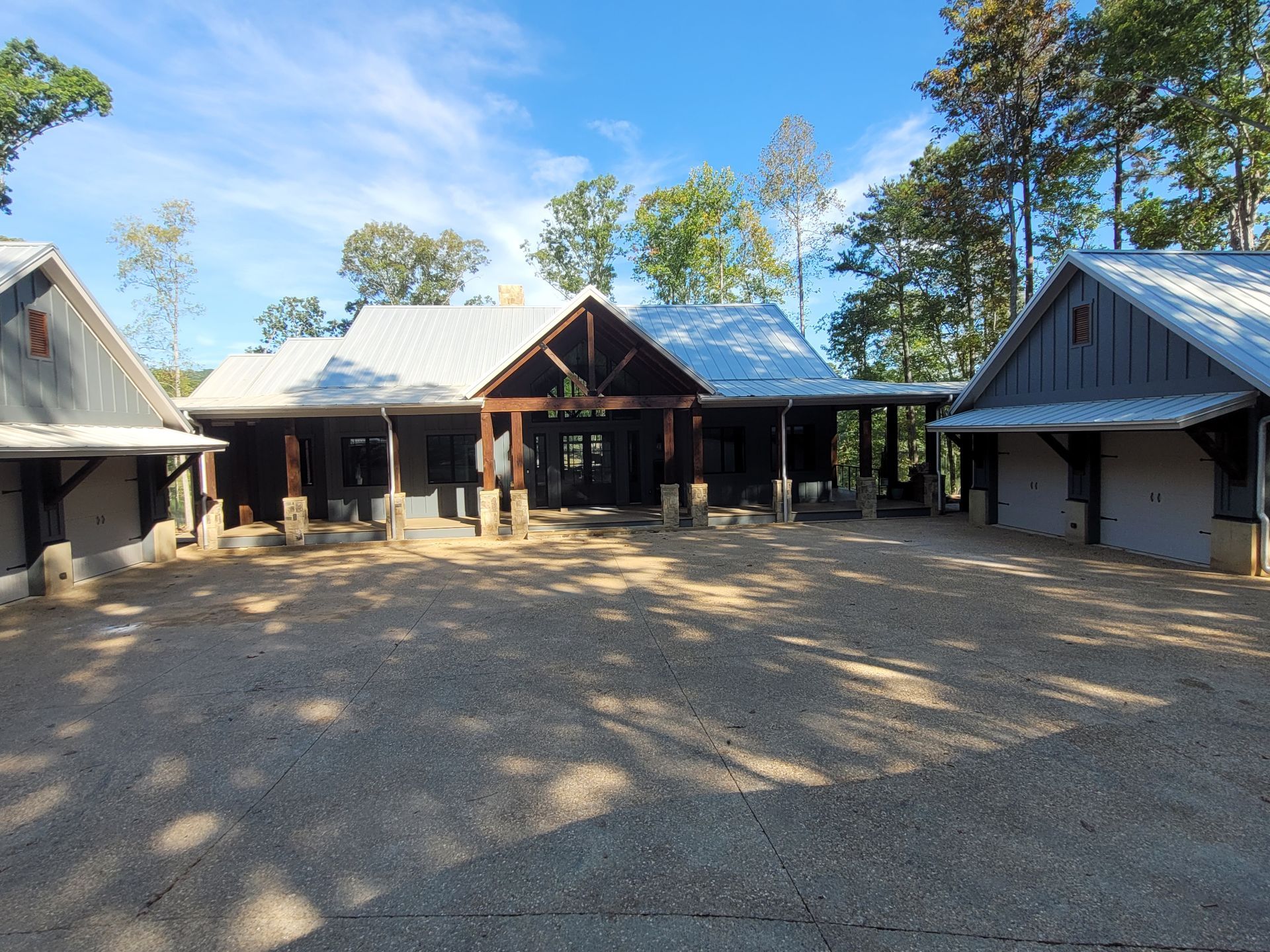 Rustic cabins with metal roofs, gravel drive under blue sky.