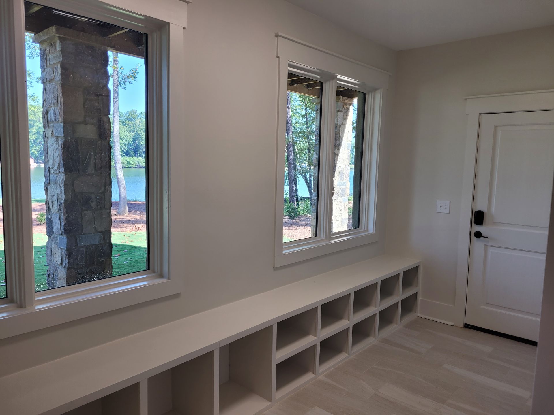 Interior room with windows, a built-in bench with cubbies, and a door.