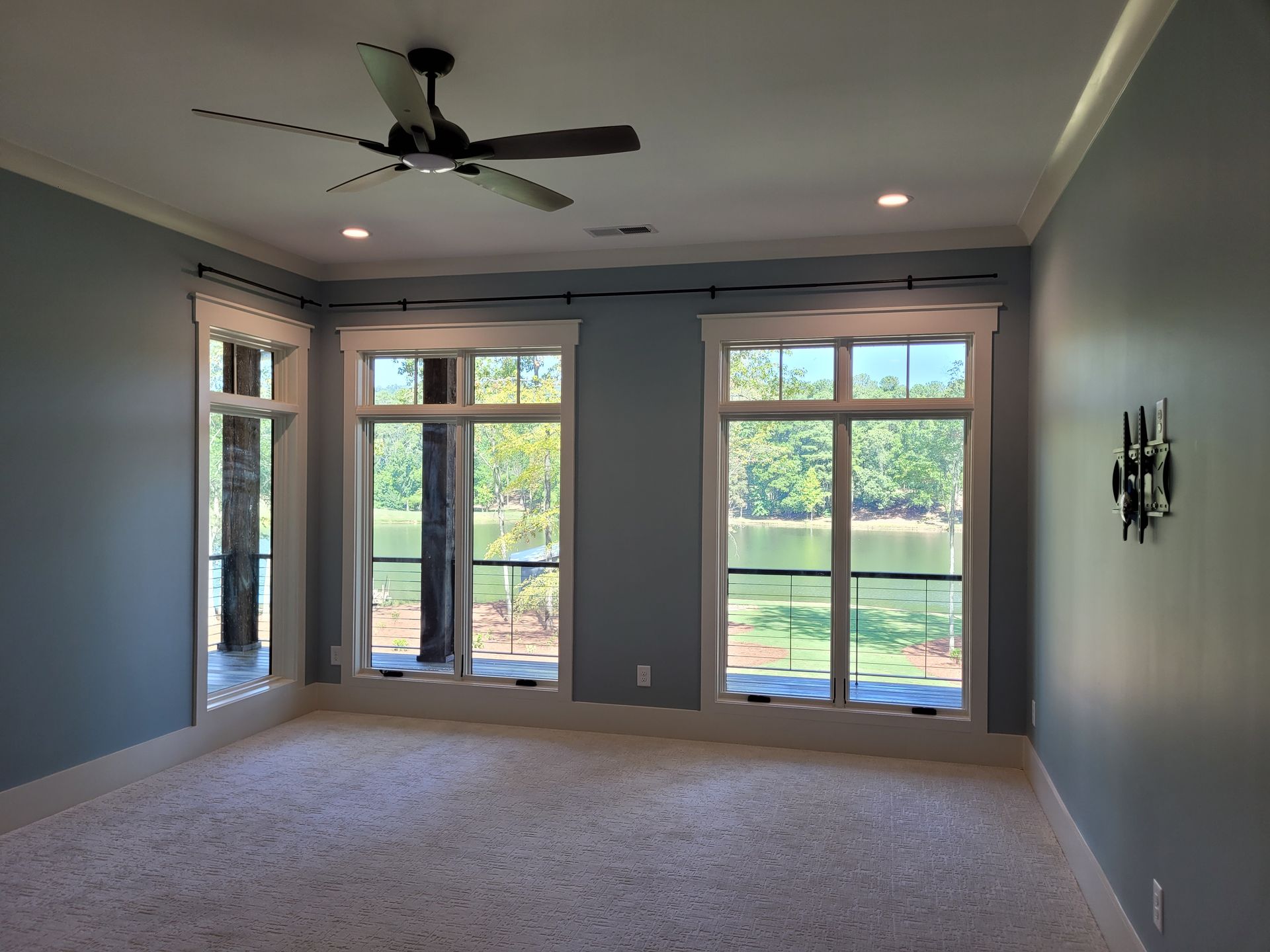 Empty room with blue walls, windows, and a ceiling fan.