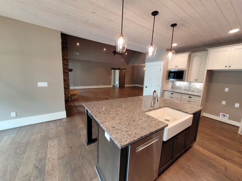 Kitchen with island, dark cabinets, granite countertop, white cabinets, wood floor, and recessed lighting.