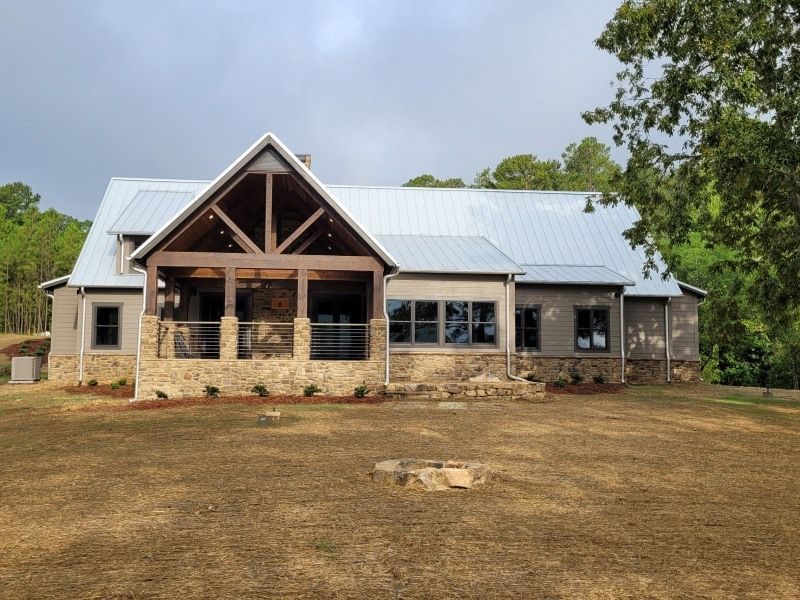 Rustic house with a metal roof, stone porch, and a fire pit in the yard.