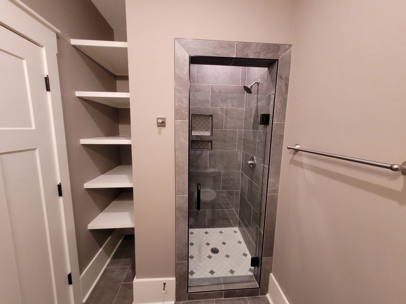 Bathroom with a glass shower, built-in shelves, and a towel rack.