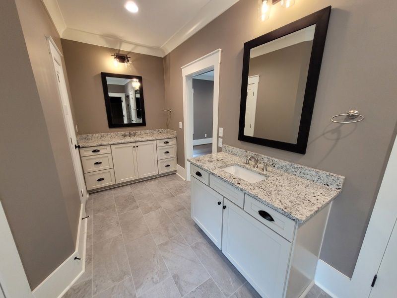 Bathroom with two white vanities, granite countertops, and gray walls.