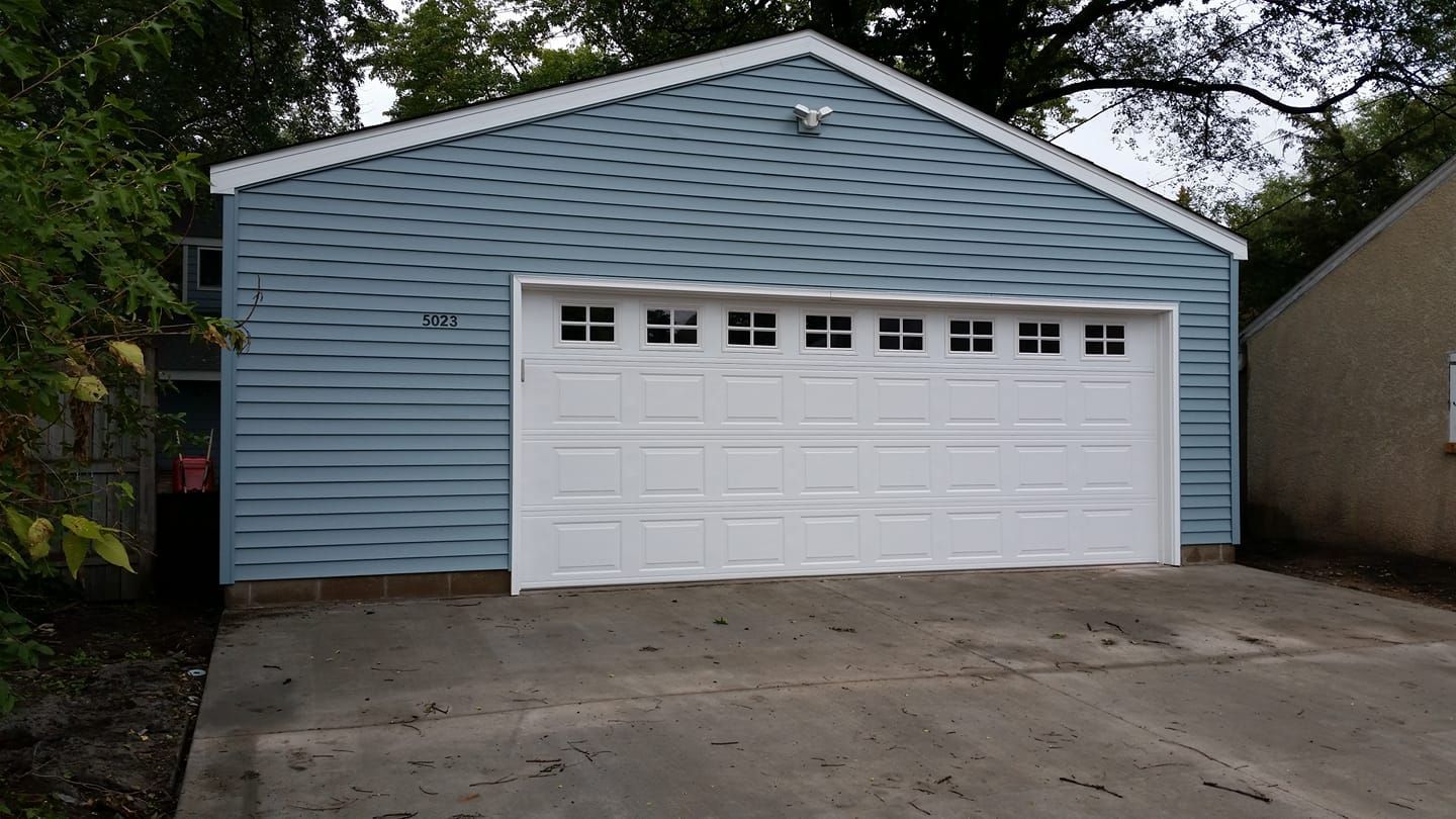 A blue garage with a white door and a driveway