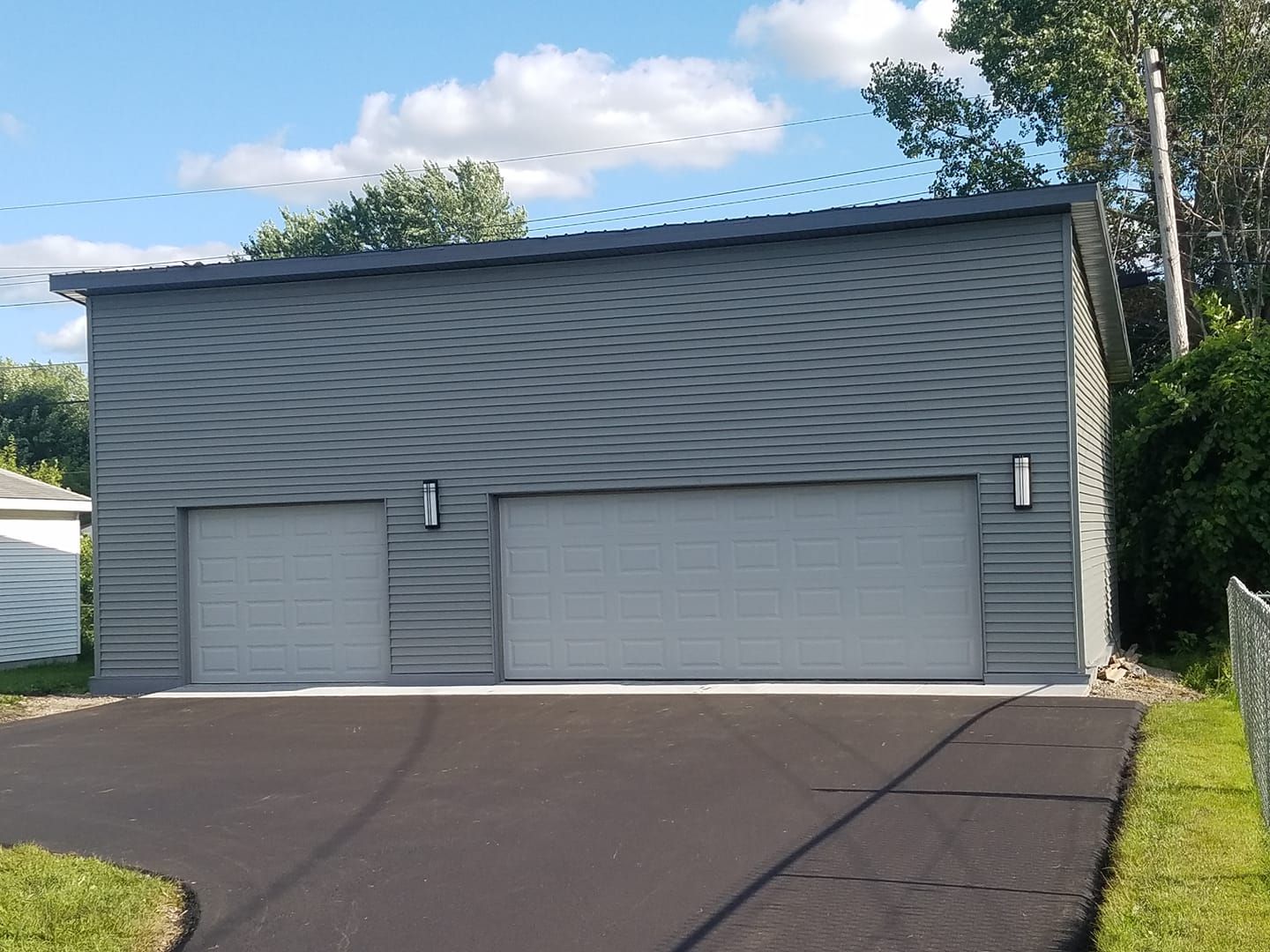 A garage with two garage doors and a driveway leading to it