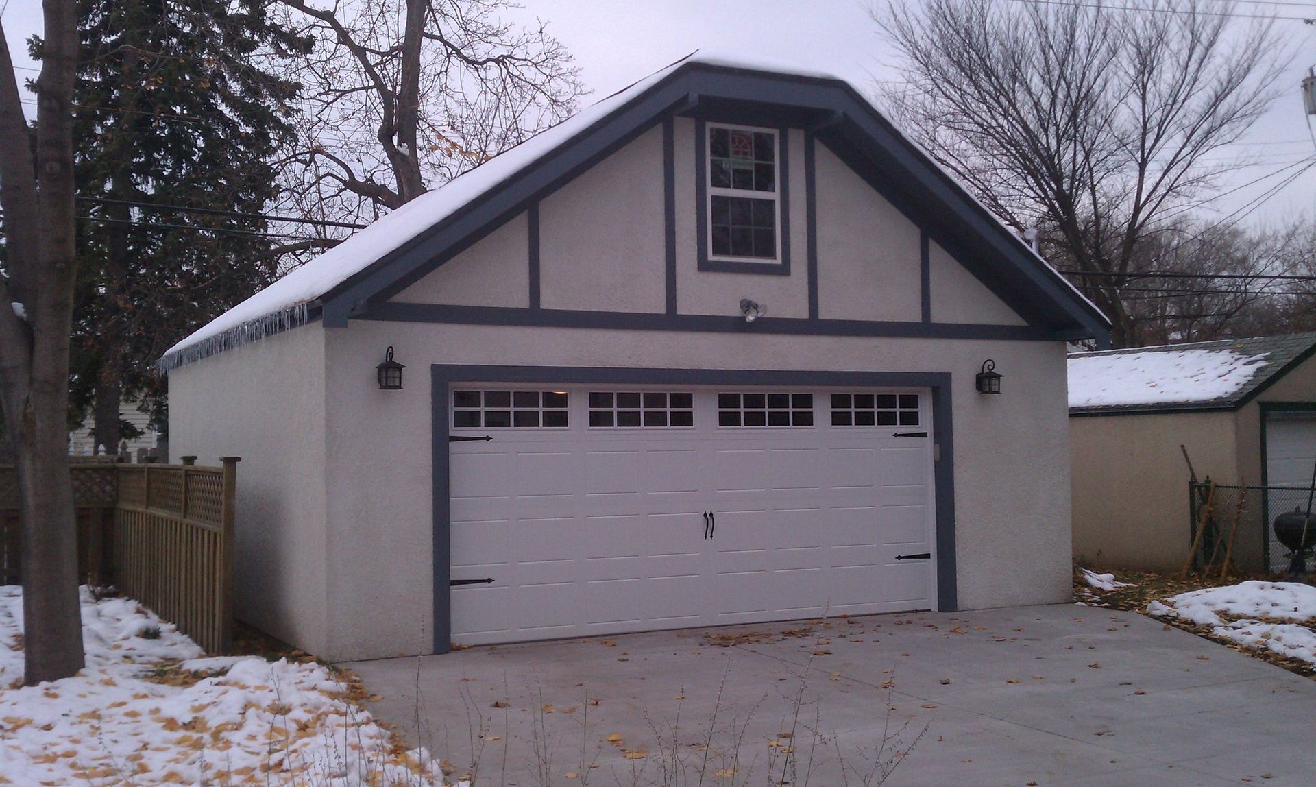 A white garage with a black roof and a window