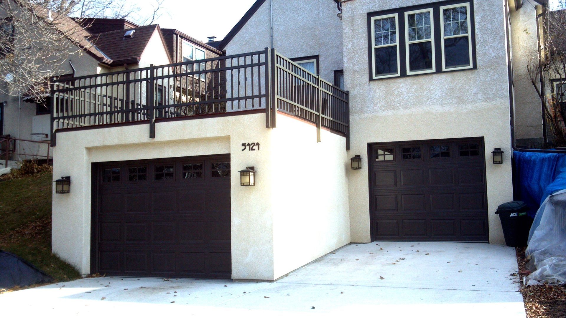 A white house with two garage doors and a balcony