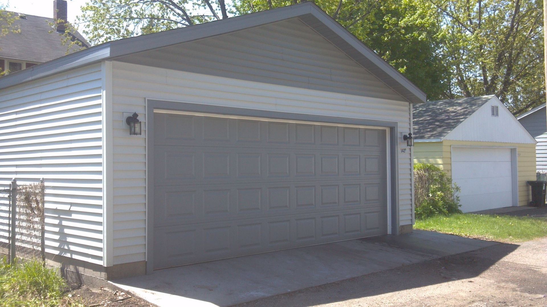 A garage with a white siding and a gray roof